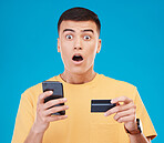 Credit card, ecommerce and man with a cellphone, surprise and transaction on a blue studio background. Person, shock and model with a smartphone, digital app and online banking with finance and fraud