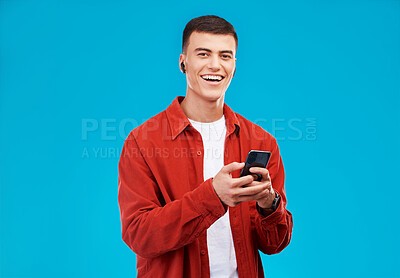 Buy stock photo Man, phone and listening to music in studio with social media, college contact and communication on a blue background. Portrait of person or student in USA with mobile, earphones or audio streaming 