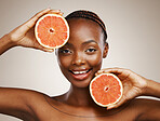 Woman, grapefruit and portrait of beauty in studio for vitamin c, vegan cosmetics and glow on brown background. Face, happy african model and citrus nutrition for healthy benefits of natural skincare