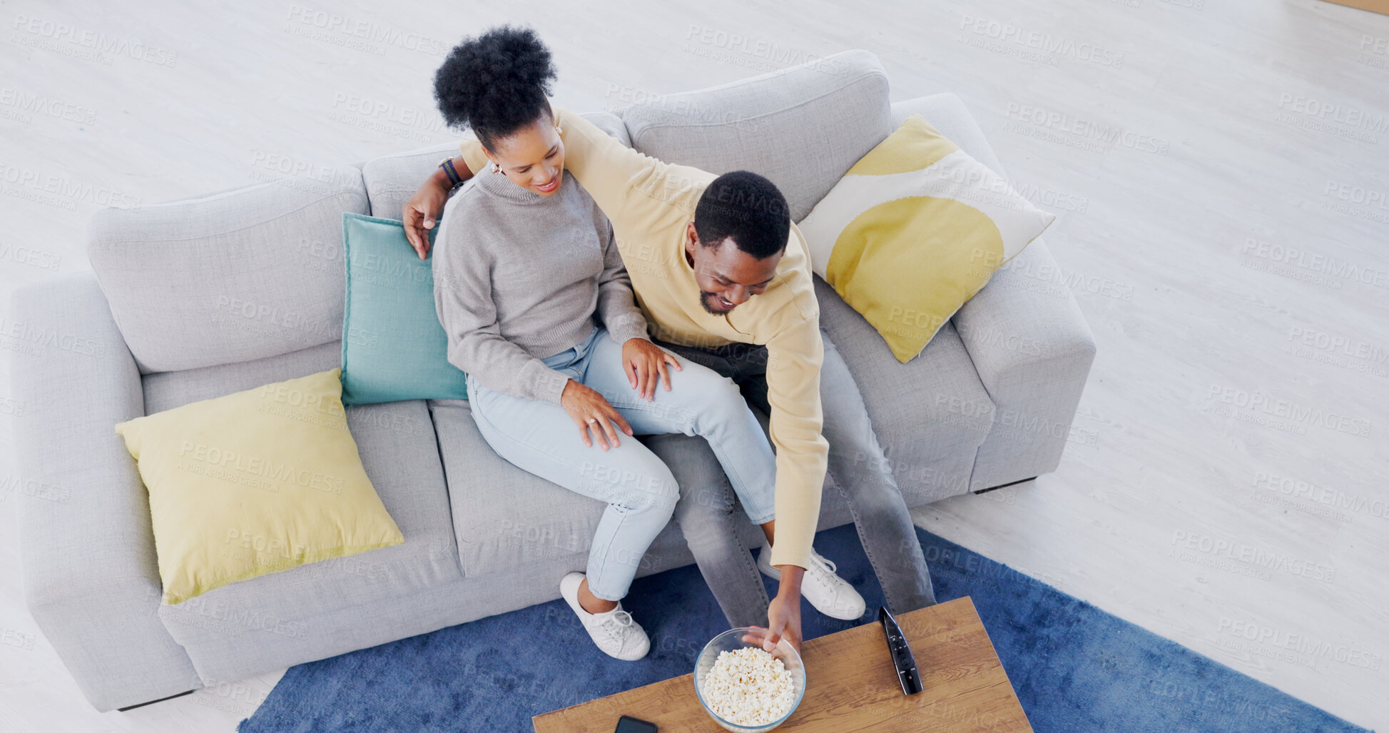 Buy stock photo Couple, watching tv and eating popcorn in home, living room and date in apartment with comedy or movies. Happy, people and together on sofa with food to watch tv show or film or above lounge in house