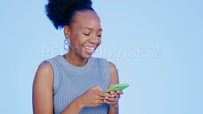 Buy stock photo Phone, smile and black woman in a studio networking on social media, mobile app or the internet. Technology, happy and young African female model scroll on website with cellphone by blue background.