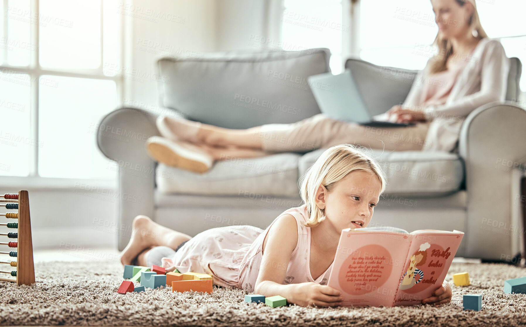 Buy stock photo Girl child, home and reading book for learning, language development and mother work from home in living room. Family, kid and English story, school education and relax on floor with mom on sofa