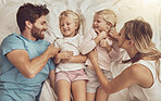 Family, children and parents in bed with smile, happiness and playing. Morning, tickle and funny with mom, dad and girls in bedroom, home and bonding together in top view, playful and affectionate