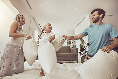 Buy stock photo Fun, happy and a family with a pillow fight in a bedroom for bonding, playful and energy in morning. Smile, excited and a young kid playing with mother and father on a bed with a game together