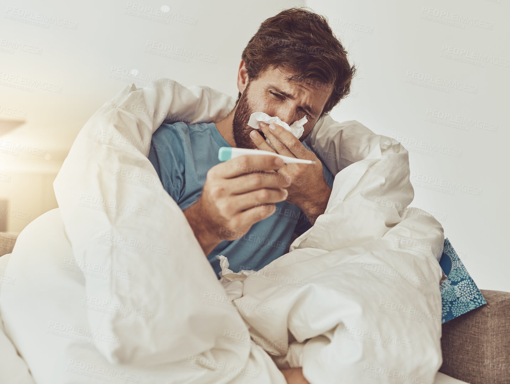 Buy stock photo Thermometer, sneeze and sick man on sofa with headache, fever or influenza crisis at home. Anxiety, high temperature and male with toilet paper, worry or blowing nose in living room with covid fear