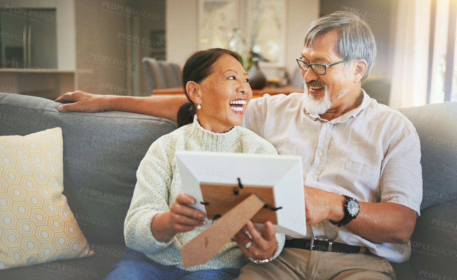 Buy stock photo Picture frame, happy and senior couple on a sofa bonding, talking and relaxing together in living room. Smile, laugh and elderly man and woman in retirement looking at photo memory in lounge at home.