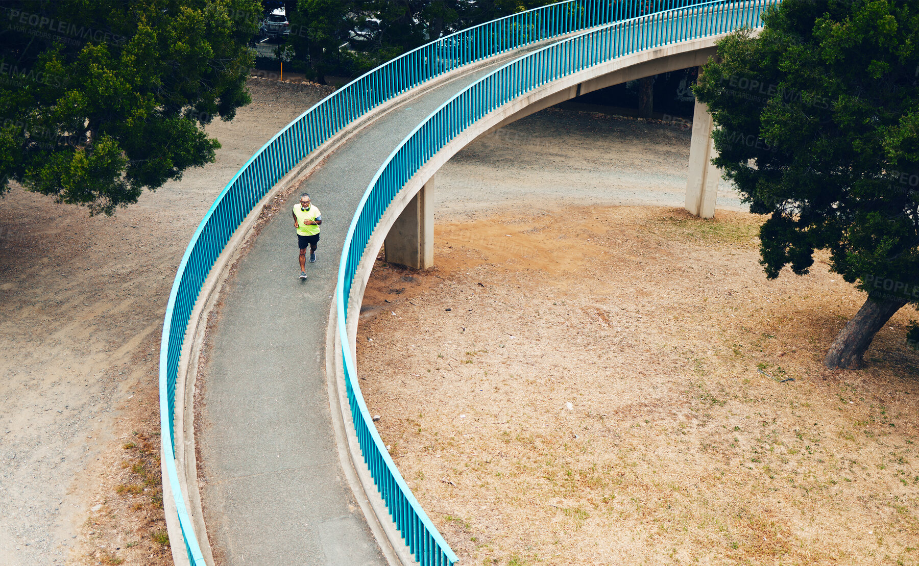 Buy stock photo Above, man and running on bridge in nature, countryside or outdoor in environment with path in woods. Athlete, run or walking on road for cardio, fitness or exercise in forest with eco infrastructure