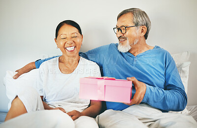 Buy stock photo Happy couple in bed, senior or surprise gift for anniversary, care or love in home, house or retirement. Eyes closed, mature Asian man or excited woman with birthday present box for romance or smile