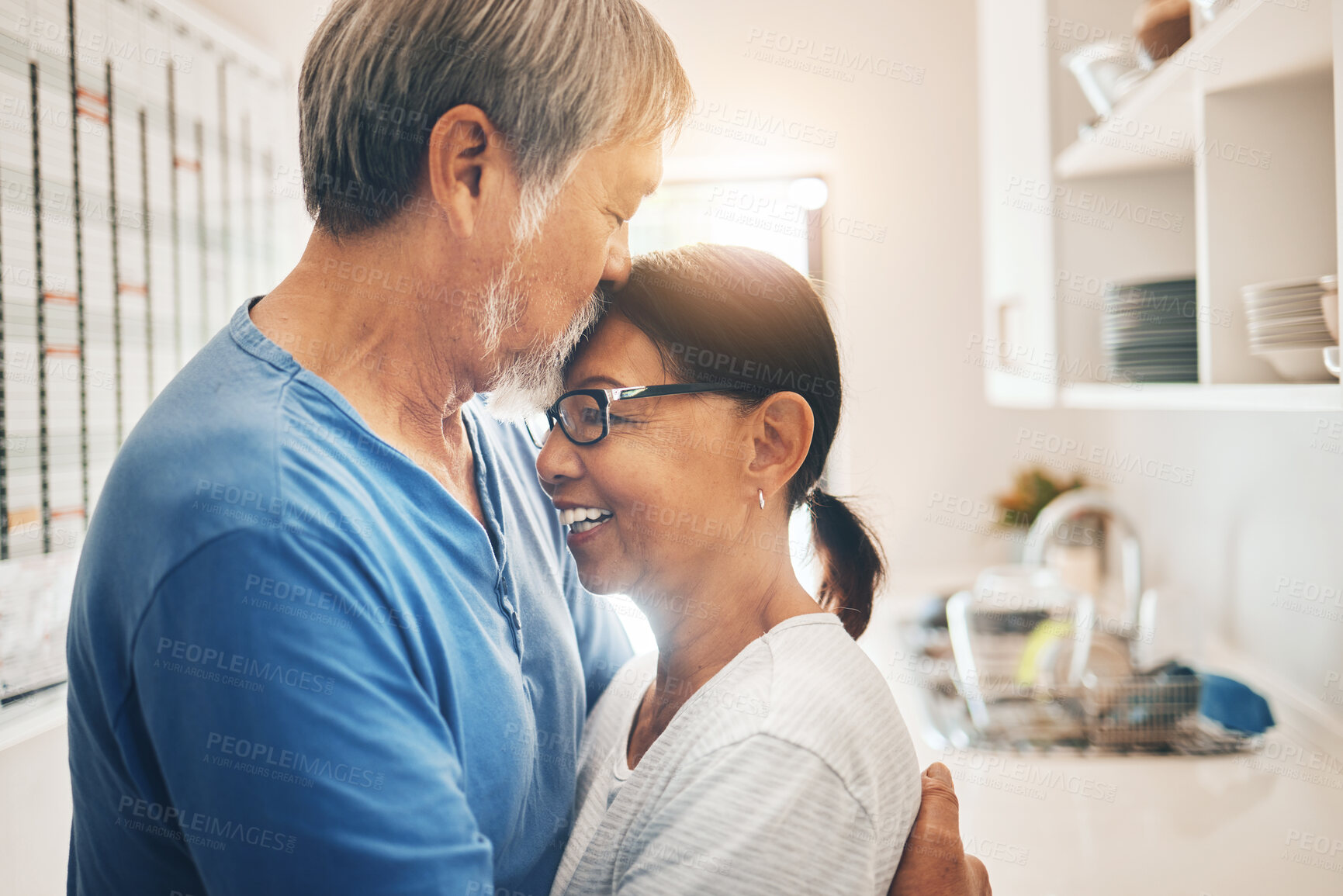 Buy stock photo Hug, smile and mature couple kiss in home for care, support or trust together. Embrace, happy man and woman in kitchen for connection, romance or healthy relationship for love, commitment or marriage