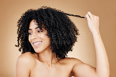 Buy stock photo Curly, hair and strand of woman in studio for natural beauty, healthy growth and coil textures on brown background. Model, smile and pull afro hairstyle for salon aesthetic, keratin treatment or care