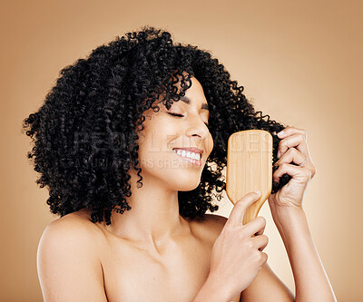 Buy stock photo Afro, hair and brush of woman in studio with smile, natural growth and healthy coil texture on brown background. Model, curly haircare and comb tools for salon aesthetic, keratin and beauty cosmetics