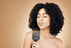 Hair care, comb and young woman in a studio with curly, natural and salon treatment. Health, beauty and female model from Mexico with cosmetic tool for healthy hairstyle isolated by brown background.