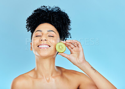 Buy stock photo Smile, skincare and happy woman with kiwi in studio for wellness, detox or natural cosmetics on blue background. Face, glow and female model with fruit for beauty, nutrition or dermatology care