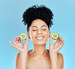 Natural, skincare and happy woman with kiwi in studio for vitamin c, collagen or wellness on blue background. Smile, face and female model with fruit for eco friendly cosmetics, beauty or skin detox