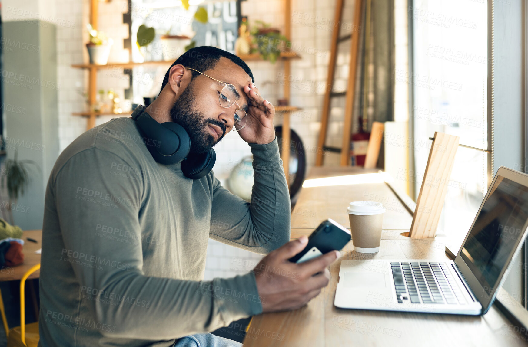 Buy stock photo Man, phone and stress in coffee shop for remote work, job search or bad news of financial fail, debt or loan. African freelancer with headache, worry or reading on mobile, business decision and cafe