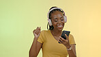 Face, woman and headphones on mobile to dance, stream music and podcast by orange background in closeup. Happy person, excited and technology with listen to playlist or audio, radio and studio mockup