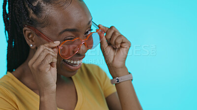 Buy stock photo Face, funny and black woman with glasses, smile and heart on a blue studio background. Portrait, African person and happy model with funky eyewear, trendy and silly with fashion, mockup or happiness