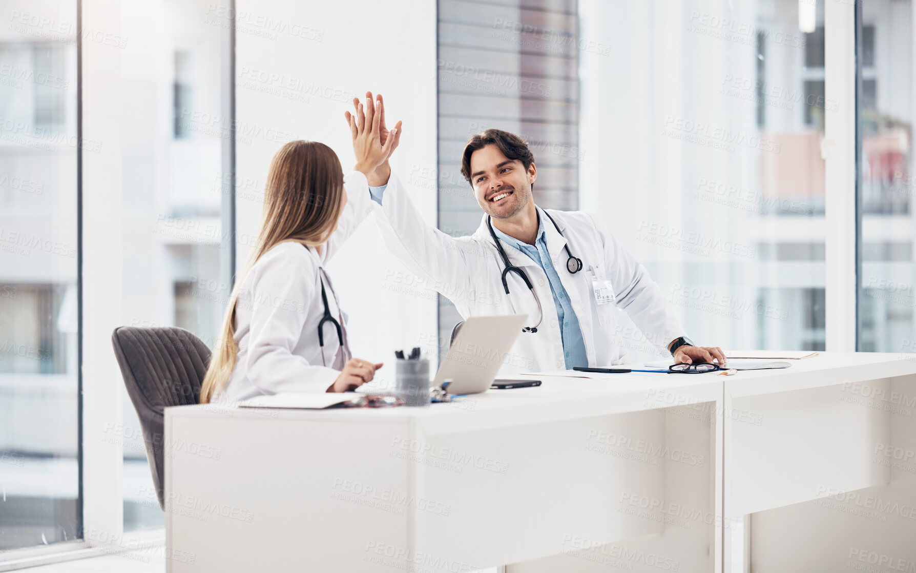 Buy stock photo Doctors, healthcare and high five for collaboration with smile at desk for planning, research and medical work in hospital. Medicine, man or woman with teamwork, coworkers or happiness for cardiology