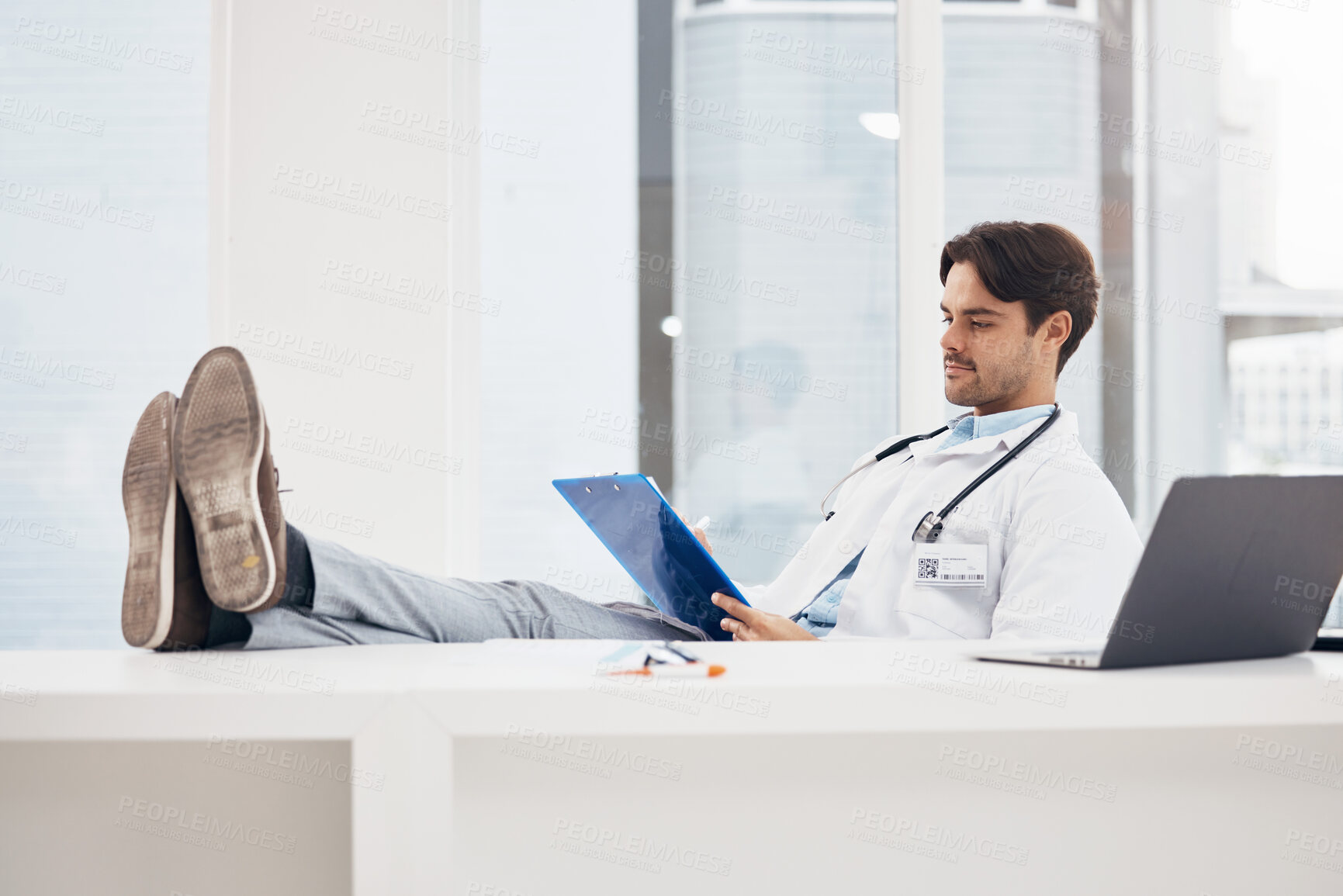 Buy stock photo Doctor, man and relax with feet on desk, reading checklist or thinking on break in hospital office. Medic, document or paperwork for report, results or idea in problem solving, solution or healthcare