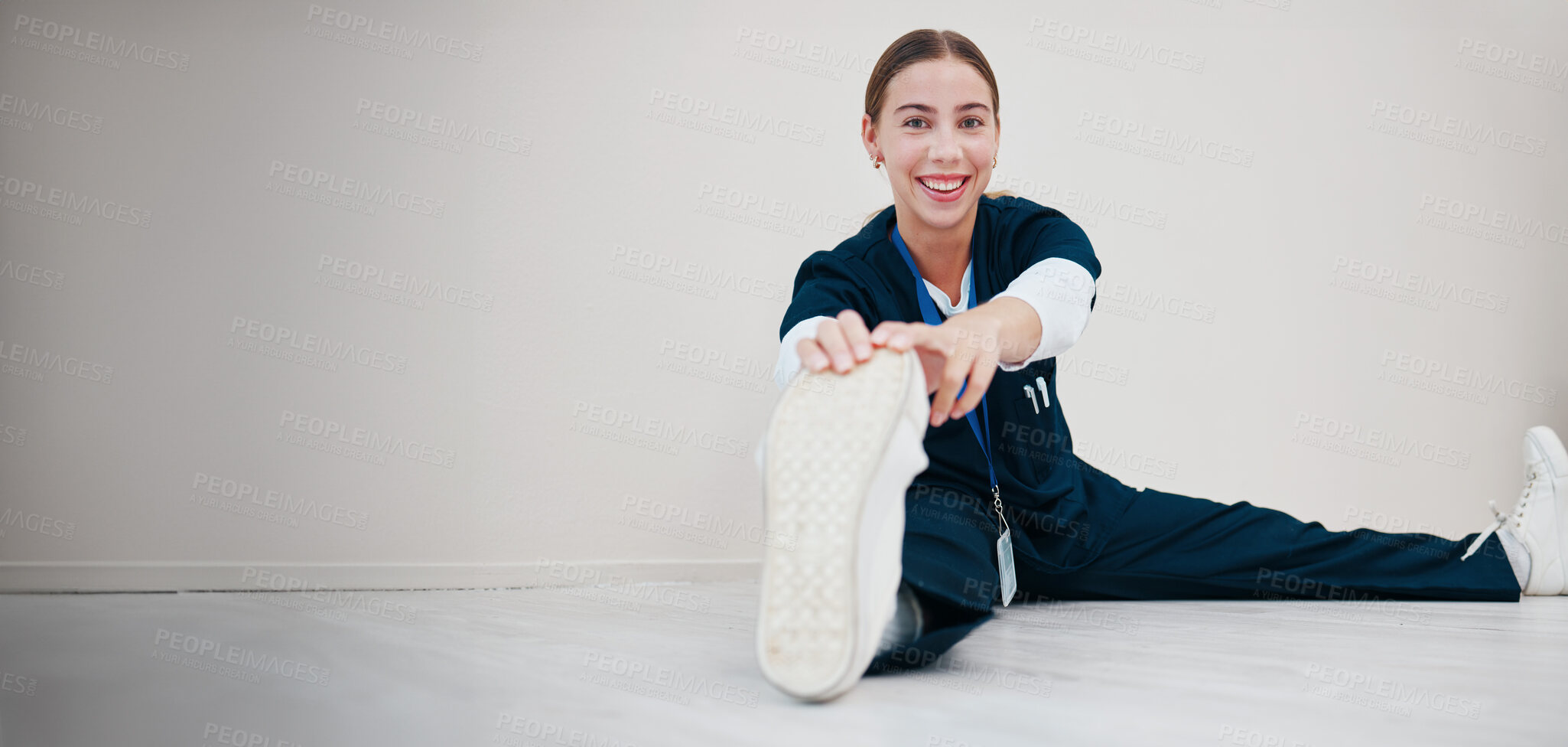 Buy stock photo Portrait, space and a nurse stretching on the floor of a studio, getting ready for healthcare or medical treatment. Smile, warm up and a happy young volunteer or medicine professional on mockup