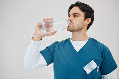 Buy stock photo Surgeon, man drinking water in bottle and health, wellness or body nutrition in studio isolated on white background in hospital. Medical professional, hydration and liquid of thirsty nurse on break