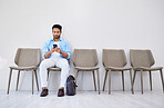 Waiting room, hiring and man in an office for interview in job search for appointment. Recruitment, career and Indian male person networking on a phone for meeting with human resources in workplace.