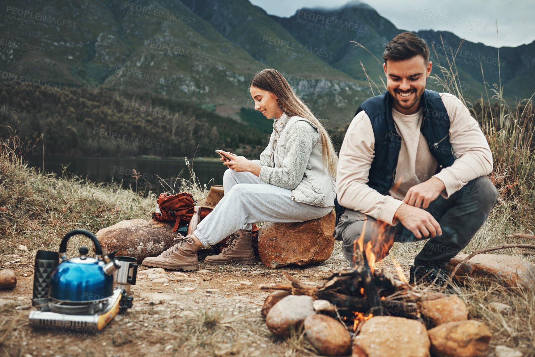 Buy stock photo Wood, nature and couple with fire on a camp on a mountain for adventure, weekend trip or vacation. Stone, sticks and young man and woman making a flame or spark in outdoor woods or forest for holiday