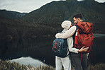 Hiking, couple and hug by a lake with camping and trekking together with love and back. Mountain, holiday and travel in the morning with a happy woman and man on adventure in nature with a smile