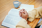 Hands, bible and praying at table, religion and Christian worship in home at desk. Closeup, holy book and woman in meditation for God, Jesus and Christ for faith in spiritual gospel, praise or hope