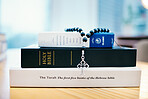 Books, stack and closeup on table for faith, Abrahamic religion or rosary with crucifix for study in home. Knowledge, holy spirit and education with cross for Jesus, Muhammad or Moses with solidarity