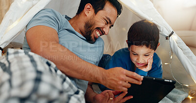Bonding, tablet and father in a tent with kid watching a movie, video or show online. Happy, smile and young dad networking on social media with boy kid on digital technology in blanket fort at home.