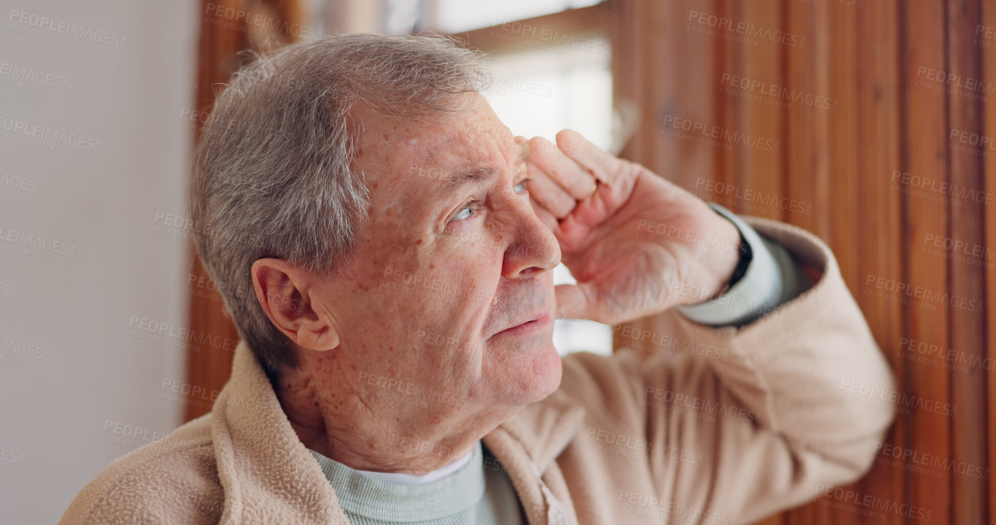 Buy stock photo Depression, sad or nostalgia with a senior man looking through a window in his home during retirement. Thinking, memory or the past with an elderly person feeling lonely in the living room of a house