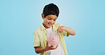 Piggy bank, cash and child face with money, savings and cash planning in a studio, Happy, portrait and young boy with allowance and safe for bills, wealth and budget with blue background and smile