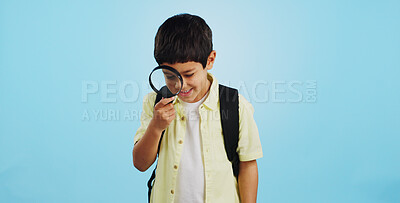 Search, looking and a child with a magnifying glass on a blue background for inspection or education. Studying, learning and a boy kid with tools for research, detective work or curious with a lens