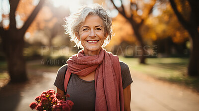 Senior female walking in park holding flowers. Confident smile. Looking at camera.