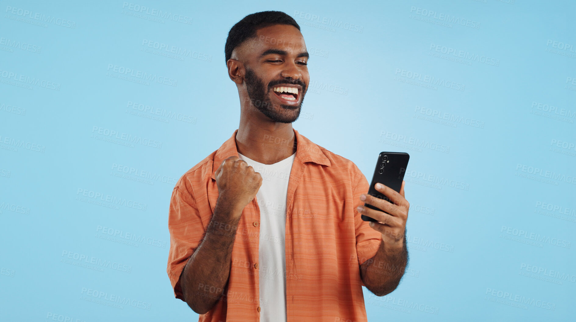 Buy stock photo Man, fist celebration and phone in studio for esports, gambling and profit with trading by blue background. African person, investor and smartphone with fintech app, lotto and revenue on stock market