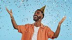 Man, birthday party hat and confetti in studio, smile or surprise for celebration by blue background. Person, event and excited with silver glitter, achievement or happy for winning with wow for goal