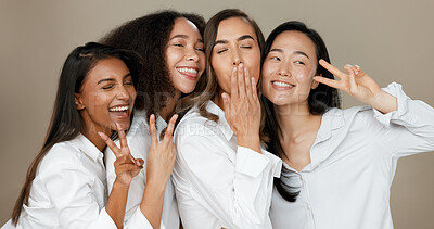 Diversity, peace sign and group of women in studio for empowerment, wellness and community. Emoji, friends and people hug, blow kiss and smile for beauty, inclusion and support on brown background