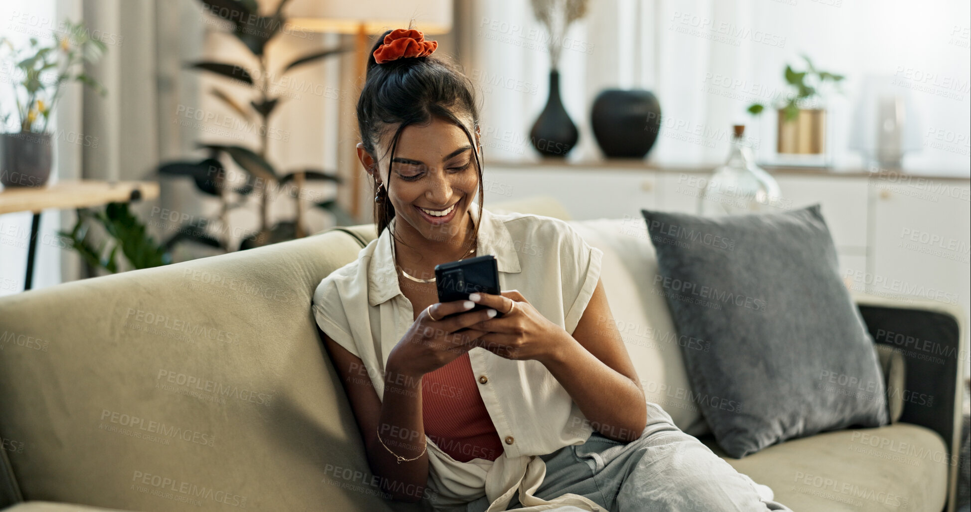 Buy stock photo Woman, smile and scroll on cellphone, social media post and update subscription app on sofa at home. Happy indian girl, smartphone and download mobile games, reading notification and chat to contact 