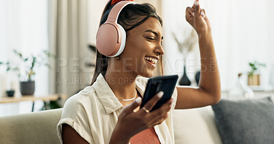 Phone, music and happy woman dance on sofa in home, singing and listening to audio. Smartphone, excited Indian person on headphones and radio, sound or freedom in living room on mobile app technology