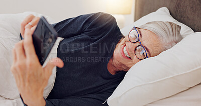 Buy stock photo Senior woman, bed and reading with phone or happy streaming funny, comedy or meme on social media. Elderly person, smile or relax with cellphone at night in bedroom with communication or online chat