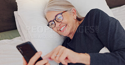 Happy, senior woman and reading with phone in bed or streaming funny, comedy or meme on social media. Elderly person, smile or relax with cellphone at night in bedroom with communication or chat