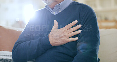 Hand, chest and heart attack with a senior man closeup on a sofa in the living room of his home during retirement. Healthcare, medical and cardiovascular disease with an elderly person in pain