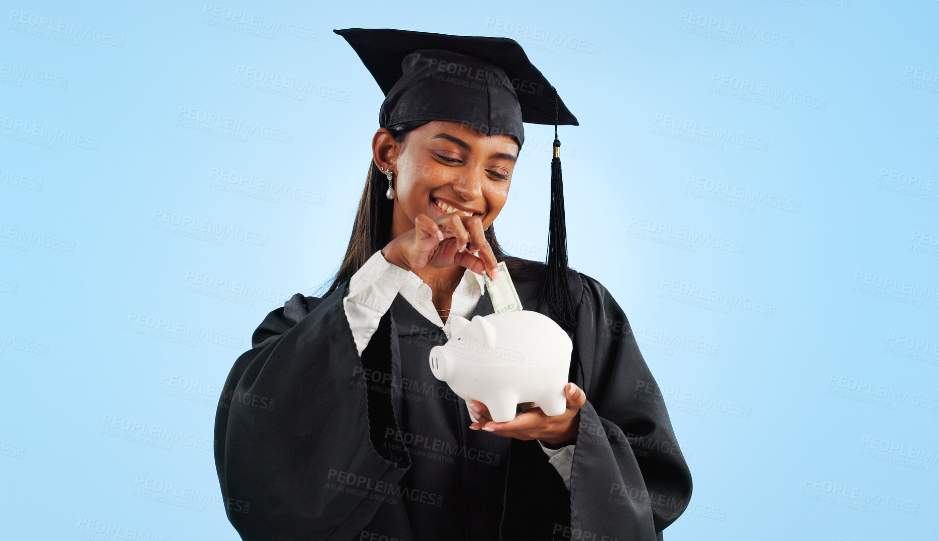 Buy stock photo Woman, graduation and piggy bank in studio, saving and cash for investing, future or goals by blue background. Student girl, banking and money with thinking, decision and choice for financial plan