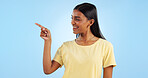 Woman, pointing and deal with marketing, information and direction for announcement in studio. Blue background, person and promotion with smile and sale with offer and show hand sign of student