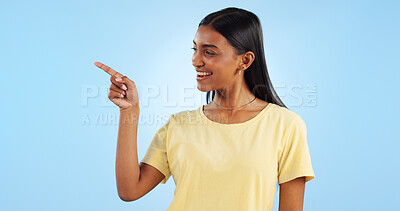 Woman, pointing and deal with marketing, information and direction for announcement in studio. Blue background, person and promotion with smile and sale with offer and show hand sign of student