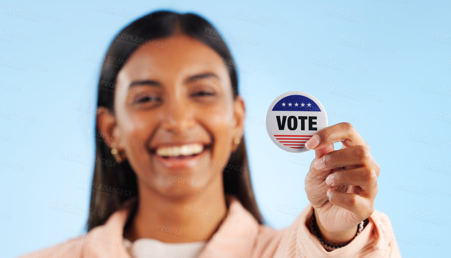 Buy stock photo Woman, hand and pin for vote by showing in studio for mock up in politics on blue background. Indian person, smile and excited for government election or campaign with support in community engagement