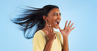 Woman, scream and wind for hair in studio for mock up on blue background with good news. Indian person, happy and smile in excitement for winning with success, celebration or announcement in space