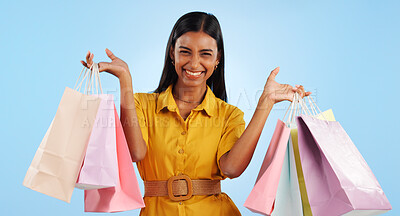 Woman, smile and happy with shopping bags in studio for marketing mock up on blue background. Indian person, face and shopaholic for fashion, cosmetics or sale by holding gifts with hands in space