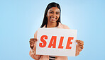 Woman, sale poster and portrait with retail, discount and billboard in studio. Excited, smile and happy from savings and deal paper with banner and promo with blue background and price decrease